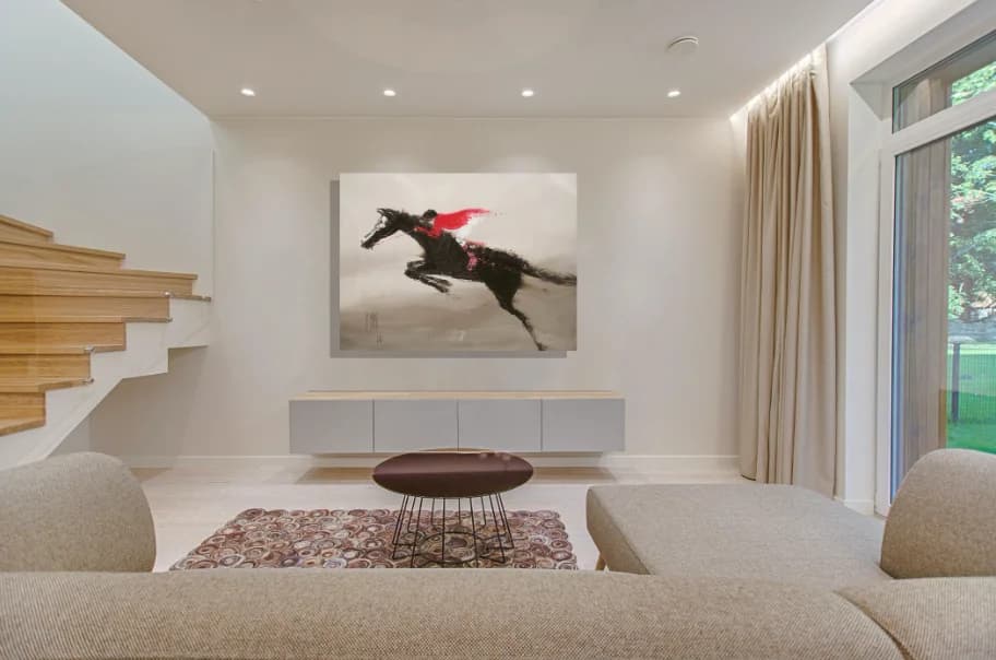 Show Jumper: leaping dark horse with red-clad rider in smoky grey tones on wall. Original painting by Kim Kennedy.