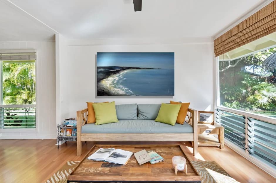 Southern Beach: moody blue coastal bay with curving white surf beach, above sofa. Original painting by Kim Kennedy.